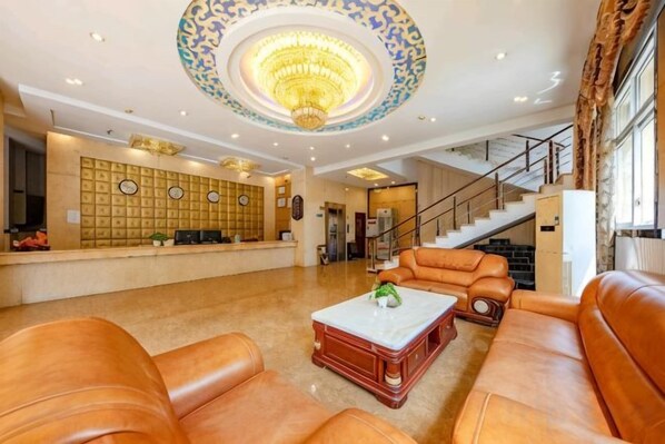 A lobby with leather sofas, a reception desk, a staircase, and a chandelier. - Huangting Holiday Hotel (Dianjiang County)