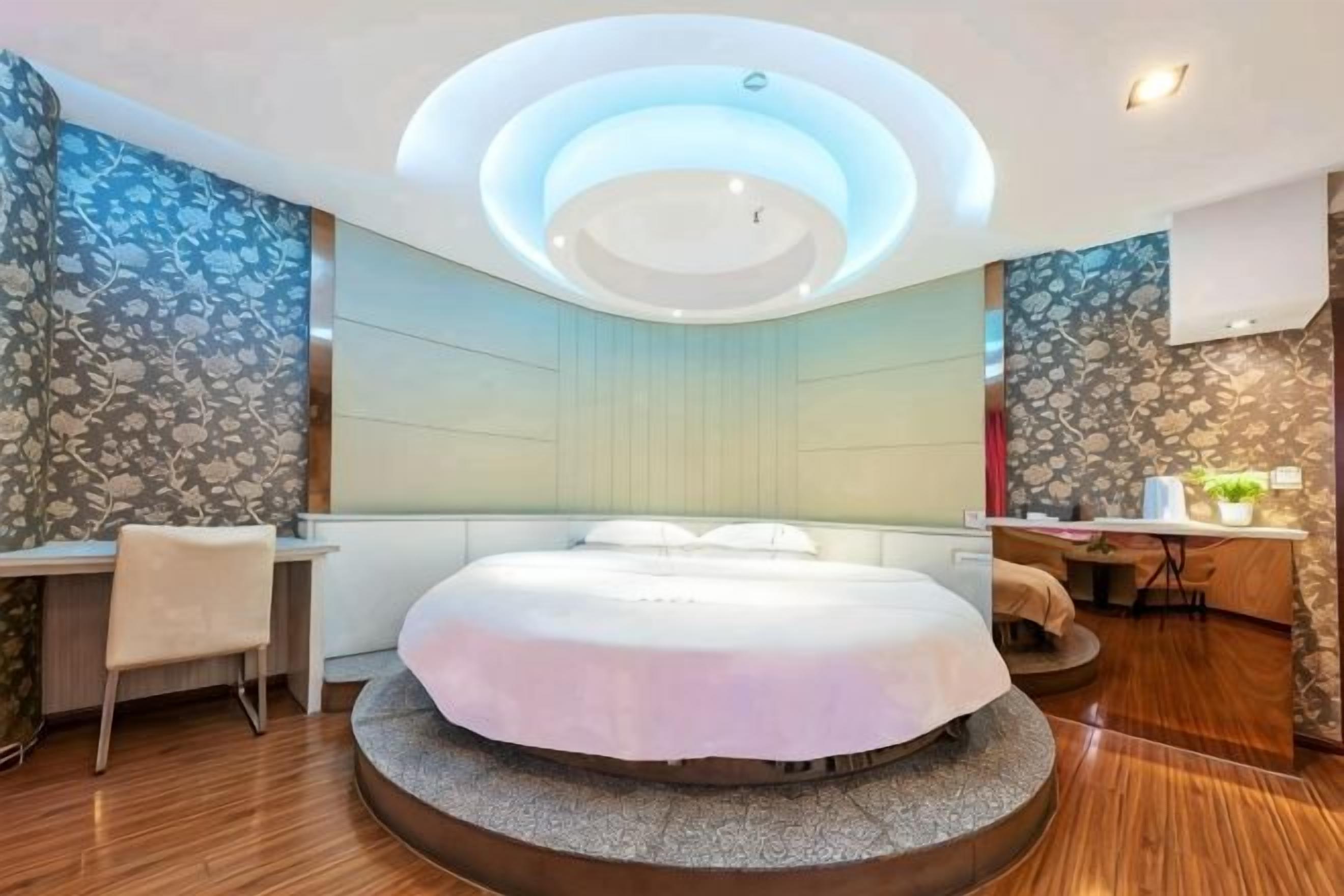 Ein modernes Schlafzimmer mit einem runden Bett, einem Schreibtisch und einem Stuhl.