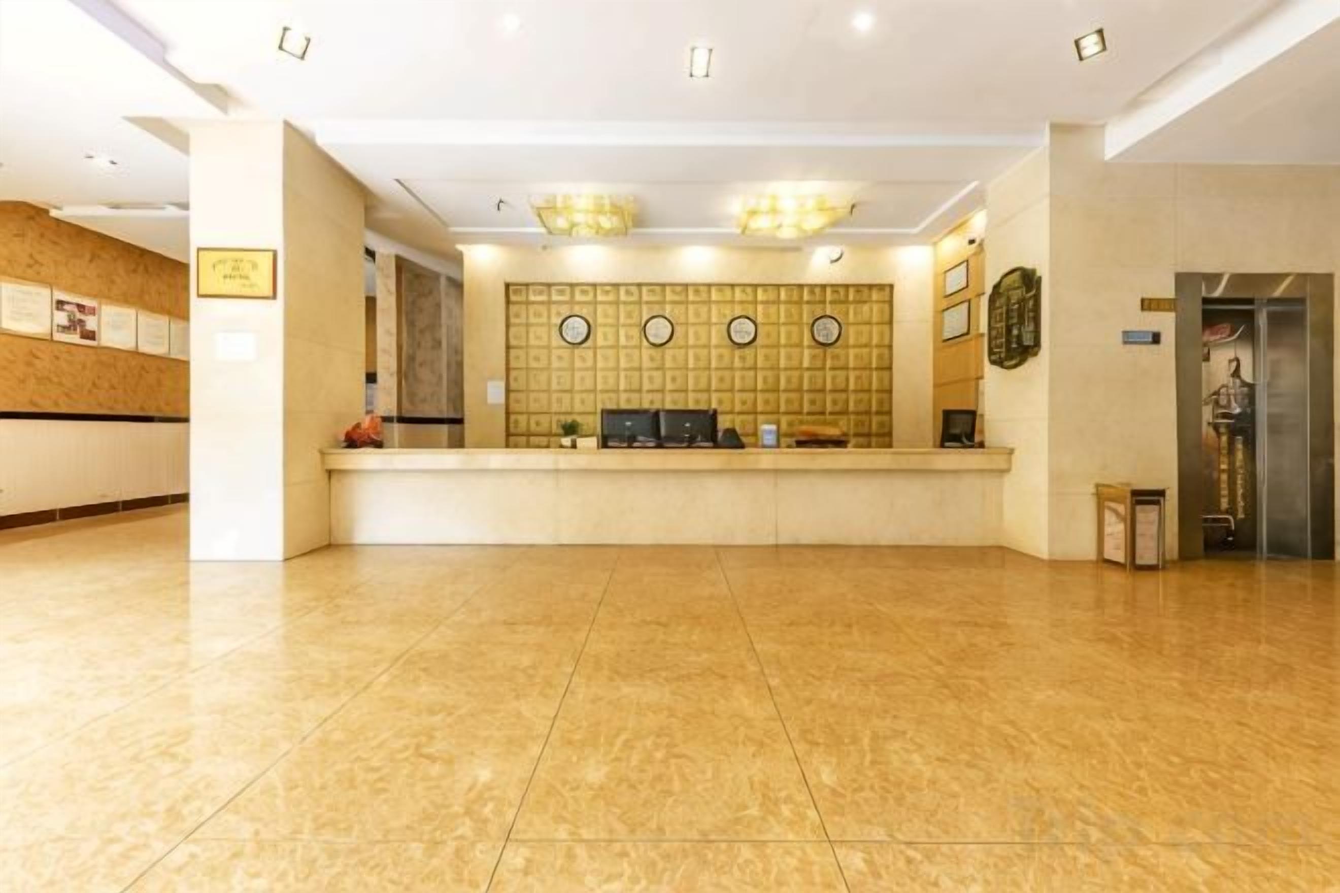 A hotel reception area with a reception desk, a large wall of circular decorative panels, and a clean, polished floor.