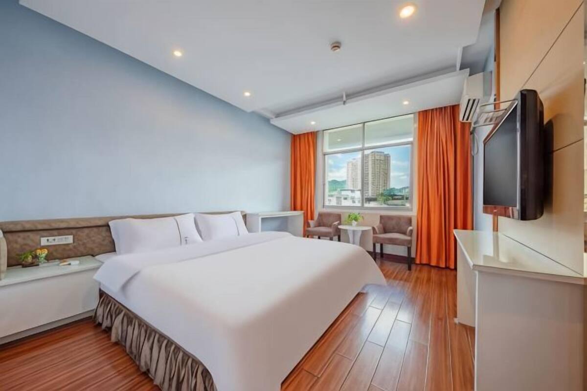 Une chambre d’hôtel avec un grand lit, un bureau, une télévision et une vue sur la ville.