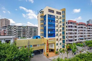 A multi-story building with a prominent entrance, surrounded by other residential buildings. - Huangting Holiday Hotel (Dianjiang County)