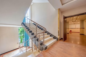 Un interior moderno con una escalera, piso de madera y vistas a través de una ventana.