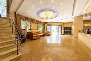 A spacious lobby with a grand staircase, a reception desk, and a seating area. - Huangting Holiday Hotel (Dianjiang County)