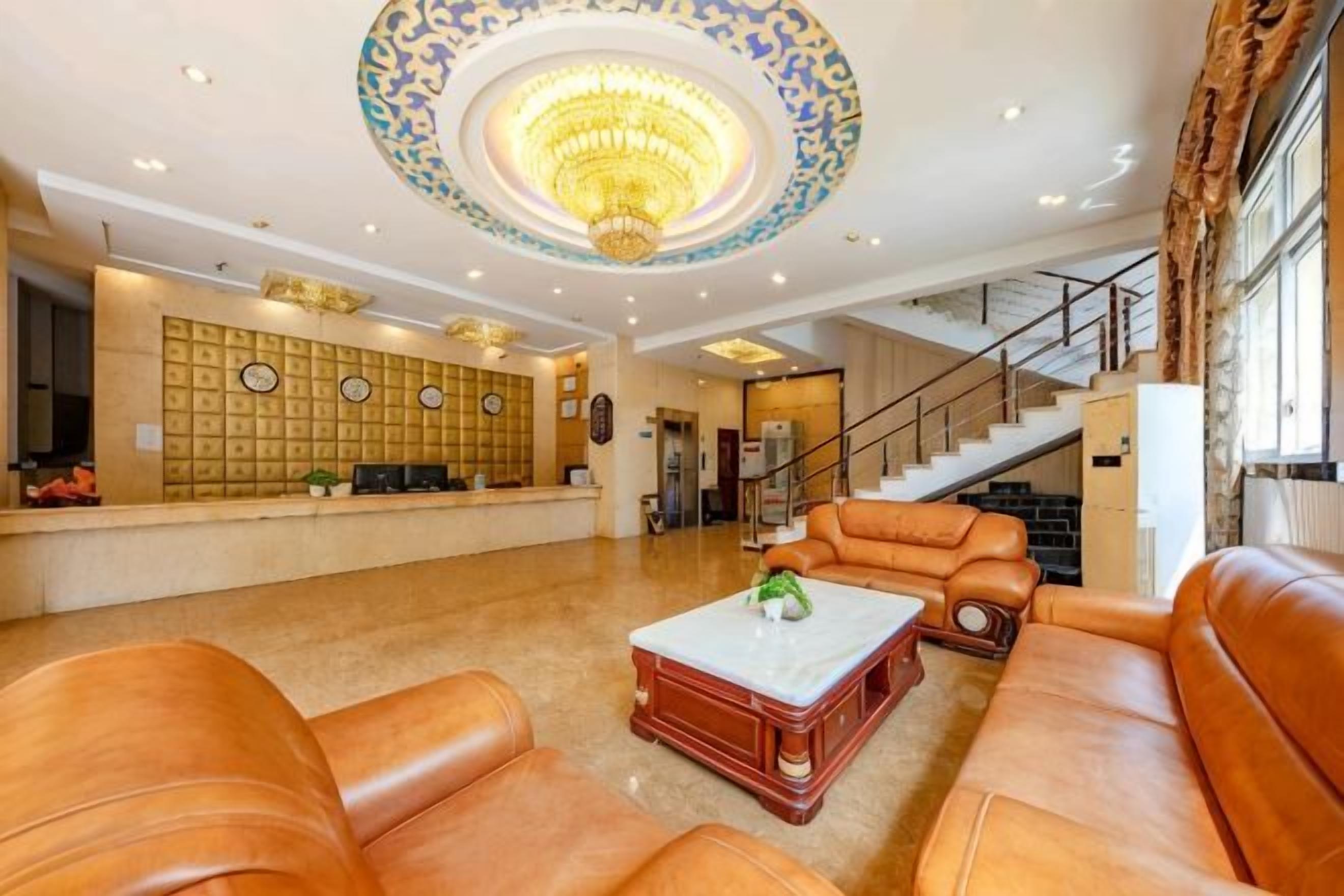 Eine Lobby mit Ledersofas, einem Empfangstresen, einer Kandelaber und einer Treppe.