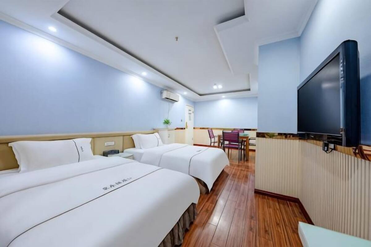 Une chambre d’hôtel avec deux lits, une télévision, un bureau et une chaise.