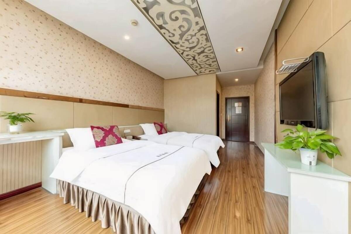 Une chambre d’hôtel avec un grand lit, une table de chevet, un miroir et une télévision.