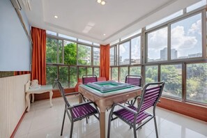 Une pièce spacieuse avec une grande fenêtre, une table avec des chaises et un radiateur.