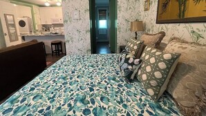 Quarto com cama, travesseiros, mesa de cabeceira e um quadro na parede.