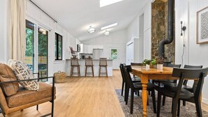 Una cucina moderna con mobili bianchi, un tavolo da pranzo in legno e una parete decorativa in pietra.