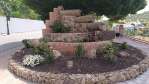 Un jardin aménagé avec une structure en briques à plusieurs niveaux, un mur de pierre et une variété de plantes et de fleurs.