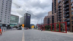 A modern urban plaza with high-rise buildings, a Ferris wheel, and a red structure. -  Spare Bedroom,  Wembley Stadium
 (London)