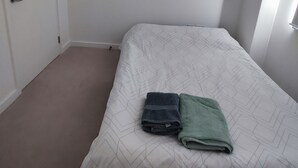 A bedroom with a bed, a door, and a window. -  Spare Bedroom,  Wembley Stadium
 (London)