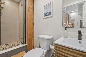 Un baño con ducha, inodoro, lavabo y un cuadro en la pared.