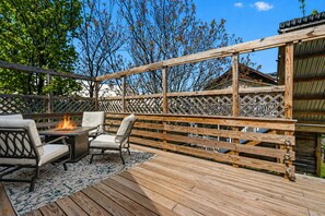 Un patio al aire libre con un hogar para fuego, dos sillas y una terraza de madera.