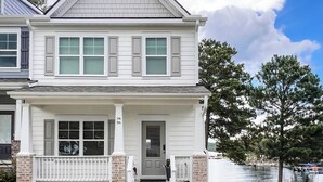 A two-story house with a front porch, a garage, and a view of a lake. - Lakefront, Dock, Kayaks, Paddleboards, Pool,Hot tub and access to boat rentals! (Eatonton)
