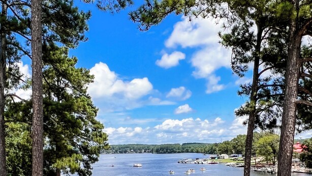 A lakeside view with docked boats, a stone structure, and a clear sky. - Lakefront, Dock, Kayaks, Paddleboards, Pool,Hot tub and access to boat rentals! (Eatonton)