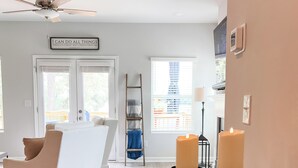 A modern living room with a white sofa, a glass coffee table with candles and flowers, and a motivational quote on the wall. - Lakefront, Dock, Kayaks, Paddleboards, Pool,Hot tub and access to boat rentals! (Eatonton)