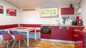 Une cuisine compacte avec une table et des chaises en bois, un four encastré et un meuble rouge.