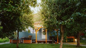 Un espace extérieur accueillant, avec des sièges, une pergola en bois, un bâtiment bleu et une enseigne indiquant un « Zweitschne ».