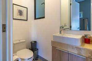 A bathroom with a toilet, a sink, and a mirror. - Camino del Tezal (Cabo San Lucas)