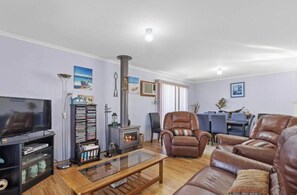 A living room with a fireplace, leather furniture, a TV, and a bookshelf.