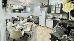 A modern kitchen with a dining area, featuring a refrigerator, microwave, and a dining table with chairs. - Luxury Suite-Unique Quotes Space (Saskatoon)