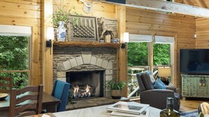 Ein gemütliches Blockhaus-Interieur mit Kamin aus Stein, Holzwänden und einer komfortablen Sitzecke.