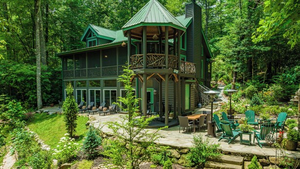 Eine Lodge mit einer großen Terrasse, Sitzgelegenheiten im Freien und einer Steintreppe, die zu einem überdachten Bereich führt.