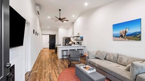 A modern living room with a sofa, a coffee table, and a kitchen area in the background. - Pet-Friendly Modern 2BR Duplex in Polson – Walk to Flathead Lake & EV Charging (Polson)