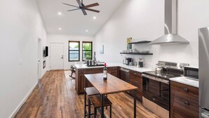 A modern kitchen with a central island, wooden flooring, and a ceiling fan. - Bear-Themed New Duplex in Polson MT – 2BR Near Flathead Lake & Glacier (Polson)