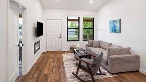 A modern living room with a sofa, a coffee table, and a TV mounted on the wall. - Bear-Themed New Duplex in Polson MT – 2BR Near Flathead Lake & Glacier (Polson)