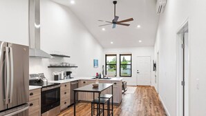 Una cocina moderna con electrodomésticos de acero inoxidable, piso de madera y un ventilador de techo.