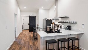 Una cocina moderna con una isla grande, suelo de madera y una puerta negra.
