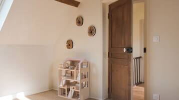 Una habitación con una puerta de madera, una casa de muñecas y tres relojes de pared.