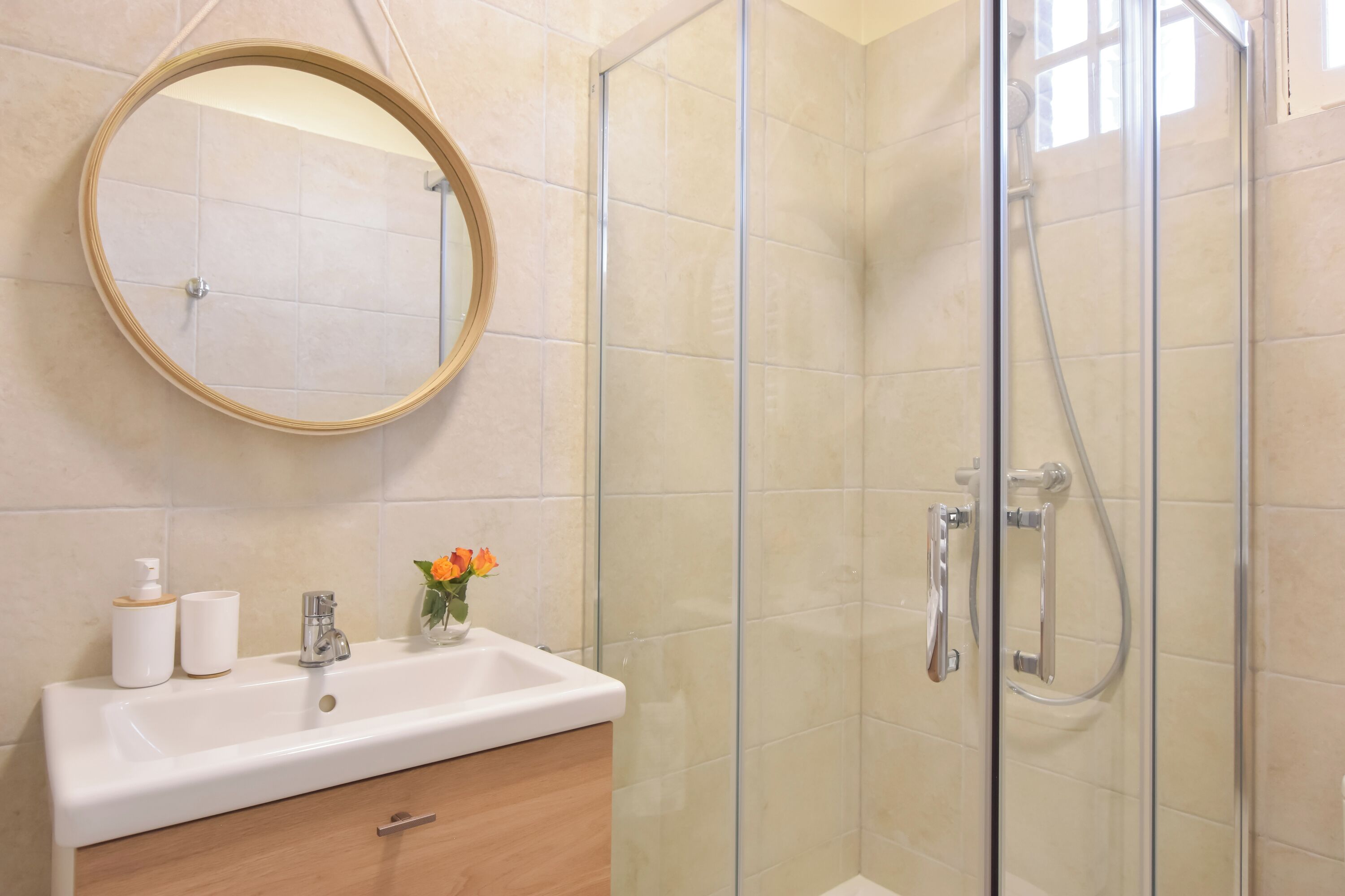 Une salle de bain avec une douche en verre, un lavabo avec un miroir et des articles de toilette.