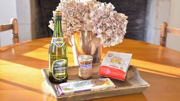 Un plateau avec une bouteille de cidre normand Andre Tallebert, un pot de confiture de pommes, un paquet de chocolat et un vase de fleurs, le tout posé sur une table en bois.
