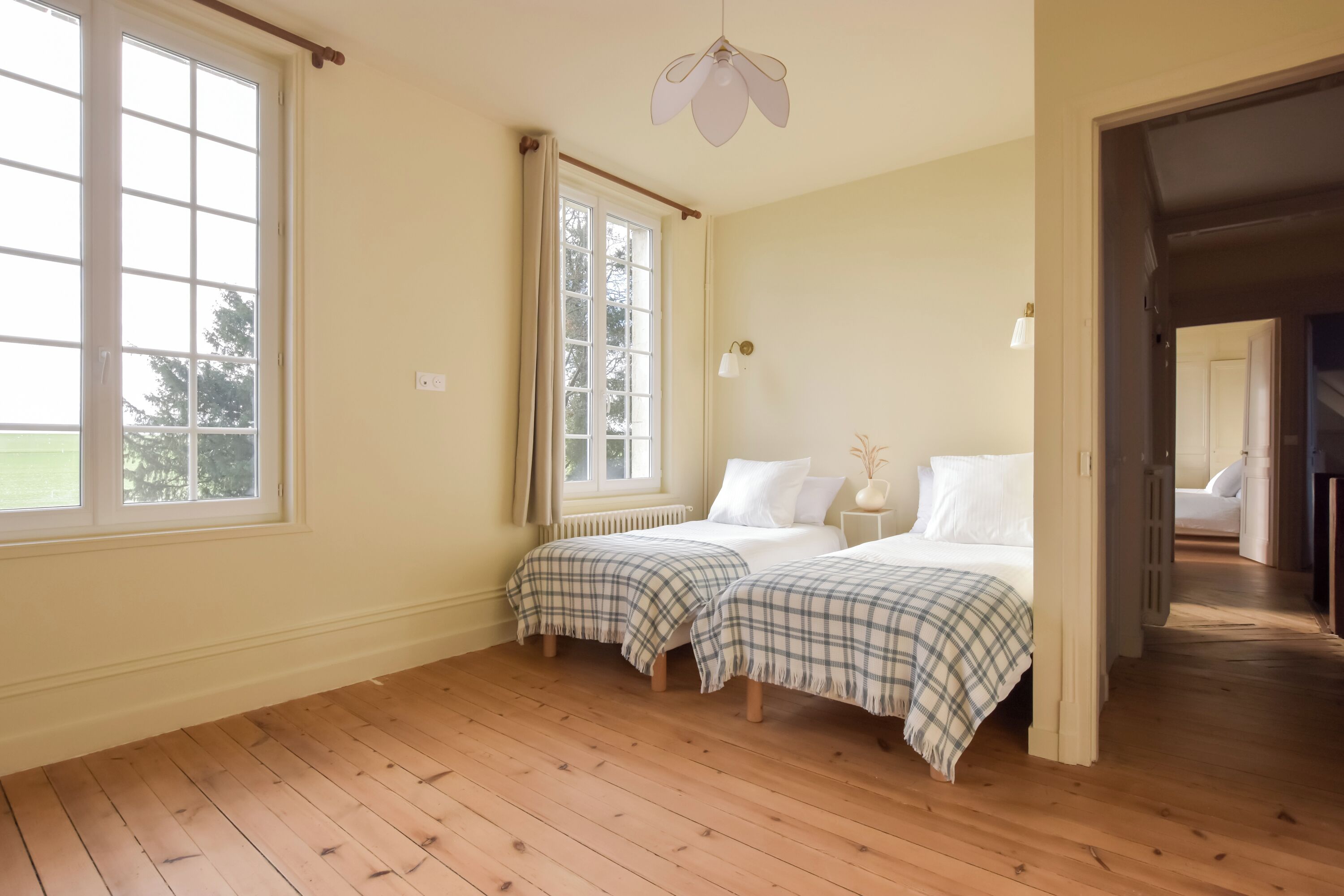Una habitación con dos camas, ventana, radiador y ventilador de techo.