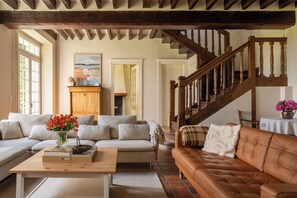 Ein geräumiges Wohnzimmer mit einer Holztreppe, einem Sofa, einem Couchtisch und einem Gemälde an der Wand.