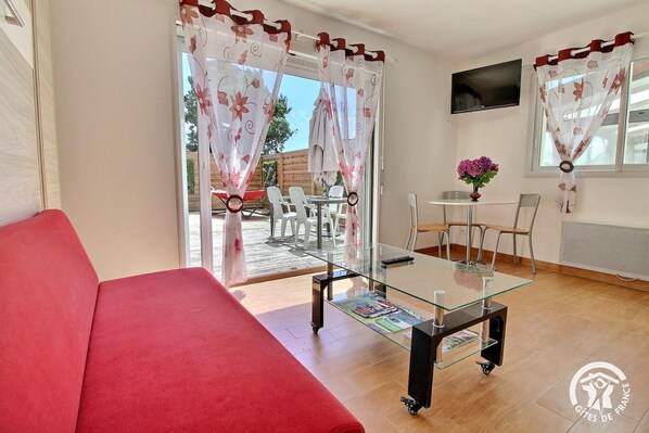 A modern living room with a red sofa, a glass coffee table, and a TV on the wall. - Impasse des Arums - Baden (BADEN)