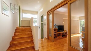 Eine Holztreppe führt zu einem Wohnbereich mit Fernseher und Holzböden.