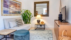 A modern living room with a sofa, a coffee table, a lamp, a mirror, and a television.