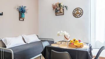 Una habitación moderna con una cama, una mesa de comedor con sillas, un reloj y objetos decorativos en la pared.