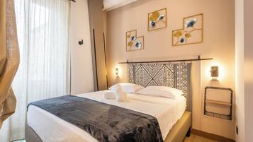 A neatly made bed with a patterned headboard, a bedside lamp, and wall art.