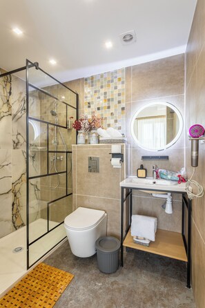 A modern bathroom with a glass shower enclosure, a white toilet, and a vanity with a mirror. - Adira Marseille Panier (Marseille)