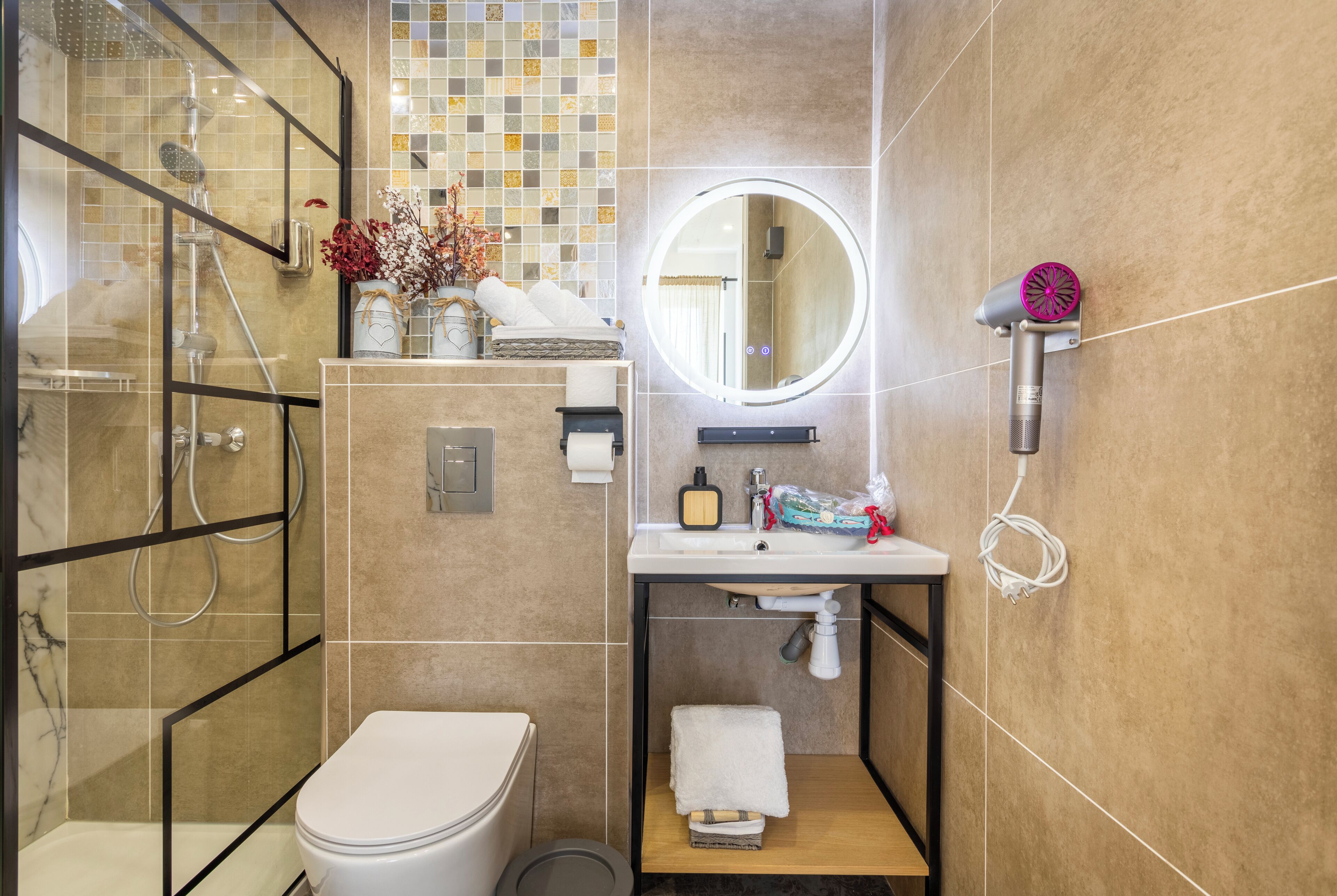 A modern bathroom with a glass-enclosed shower, a toilet, a sink with a mirror, and a towel rack.