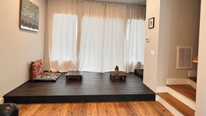 A spacious living room with a wooden floor, a large window with sheer curtains, a small table, and a couch. - Cozy townhome in charming Chattanooga downtown with fastest WiFi, sleep for 5  (Chattanooga)