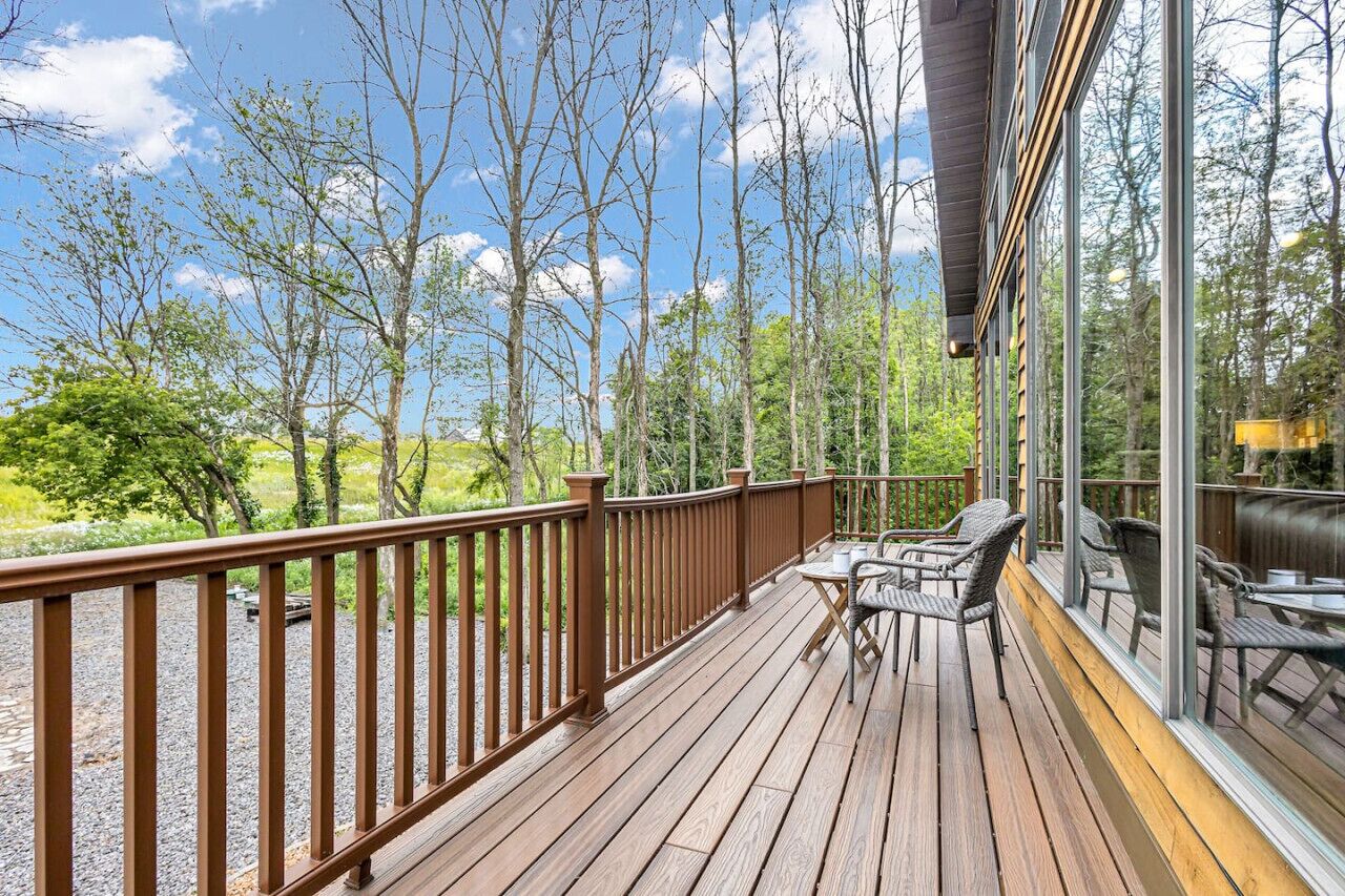 A wooden deck with outdoor furniture, overlooking a forested area.