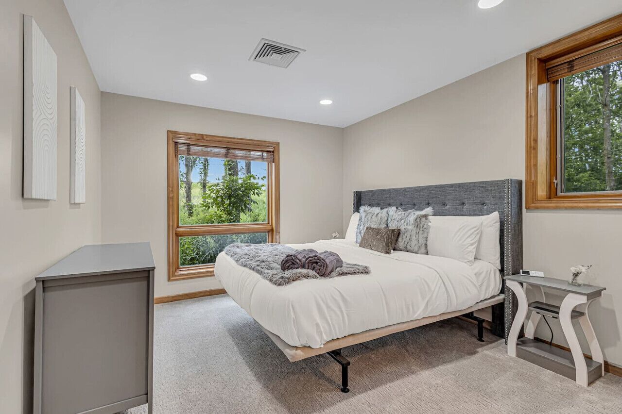 A bedroom with a bed, a bedside table, a window, and a cabinet.