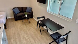 A compact living space with a sofa, a small table, a dining table with chairs, and a TV mounted on the wall. - Cozy apartment with WiFi and AC in charming El Cajon San Diego (El Cajon)