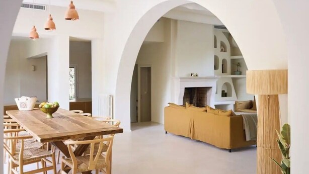 A spacious living area with a wooden dining table and chairs, a sofa, and a fireplace. - Villa El Sol Juan Les Pins (Antibes)